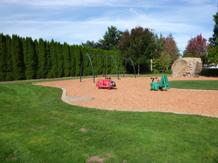 Playground on bark chip surface with access ramp – surrounded by grass